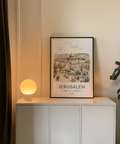 Travel-style cityscape print of Jerusalem with potted trees, rooftops, and coordinates text