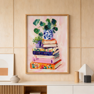 Illustrated print showing books pile topped with leafy houseplants on a light background