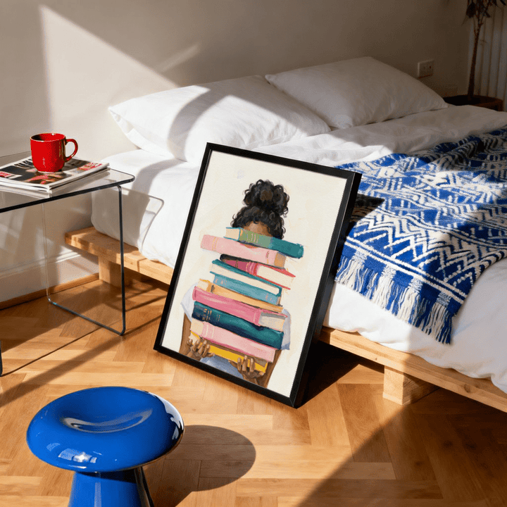 Book Lover Art Print leaning on floor with natural light in bedroom featuring blue patterned blanket