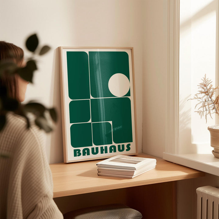 Art for Office print leaning on a desk with green geometric shapes and a beige wall plant nearby