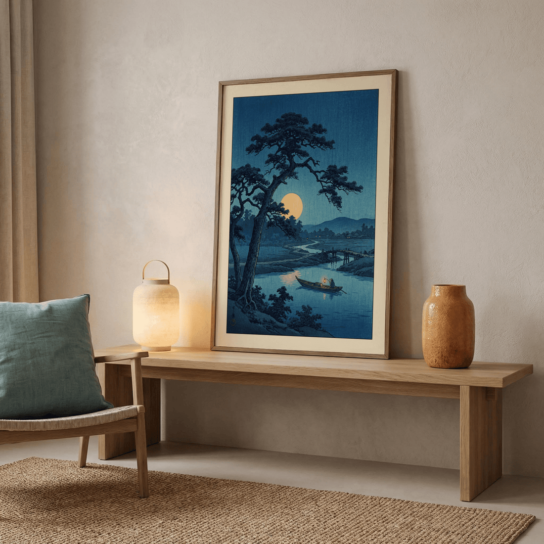 Moonlit Japanese woodblock print of a pine tree and river in a light oak frame, leaning on a low wooden bench beside a paper lantern lamp