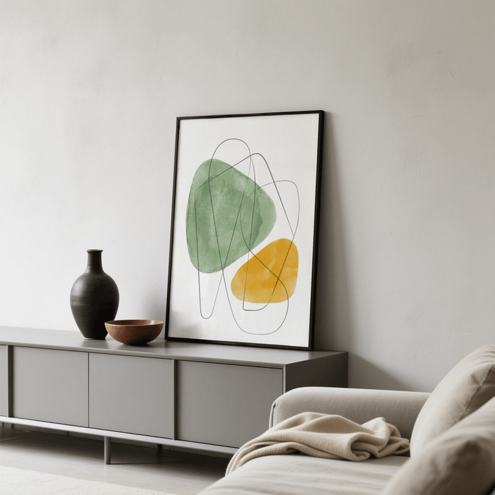 Abstract watercolor art print leaning on grey sideboard with black vase and wooden bowl in a living room