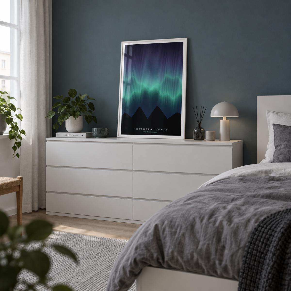 Aurora borealis over dark peaks print on a dresser against a teal wall