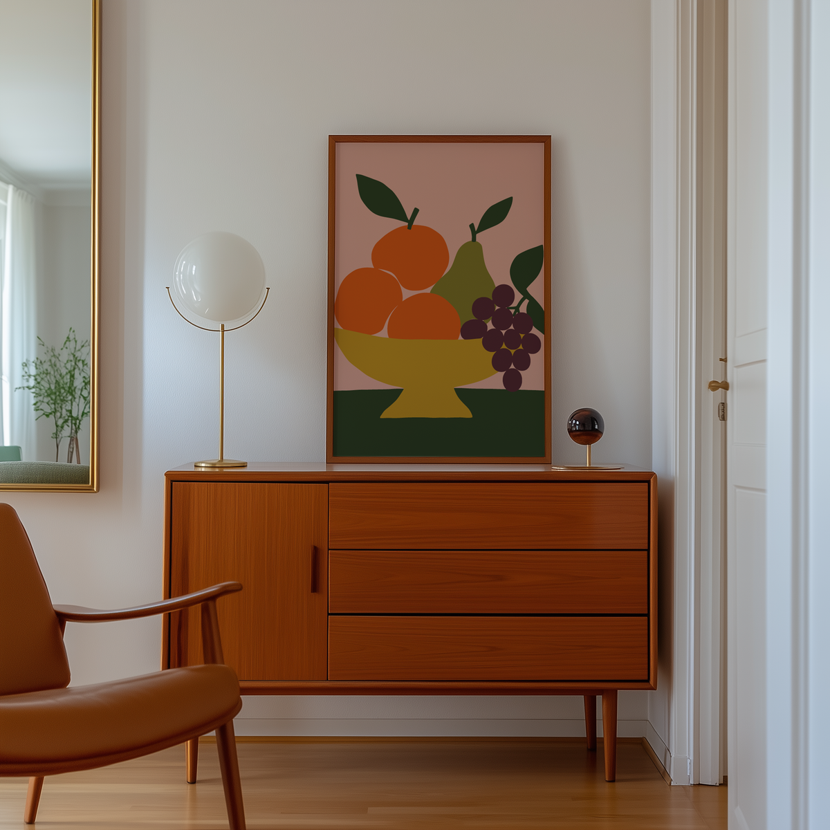 Cut paper oranges, pear and grapes print above a mid century sideboard in a hallway