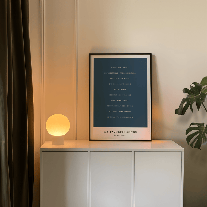 Custom Song Wall Art print leaning on a white cabinet with a glowing lamp and green plant nearby