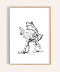 Illustrated frog reading on a toilet wall art print in black and white
