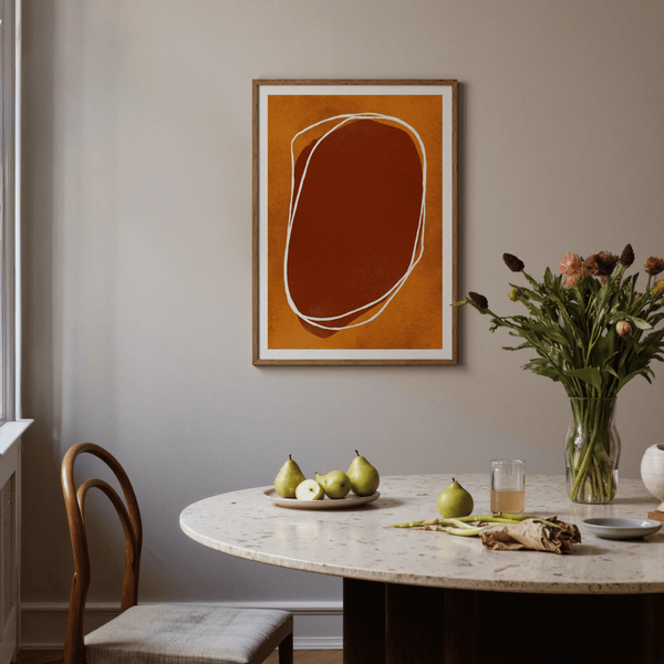 Textured rounded form art print resting on wooden shelf with small plant