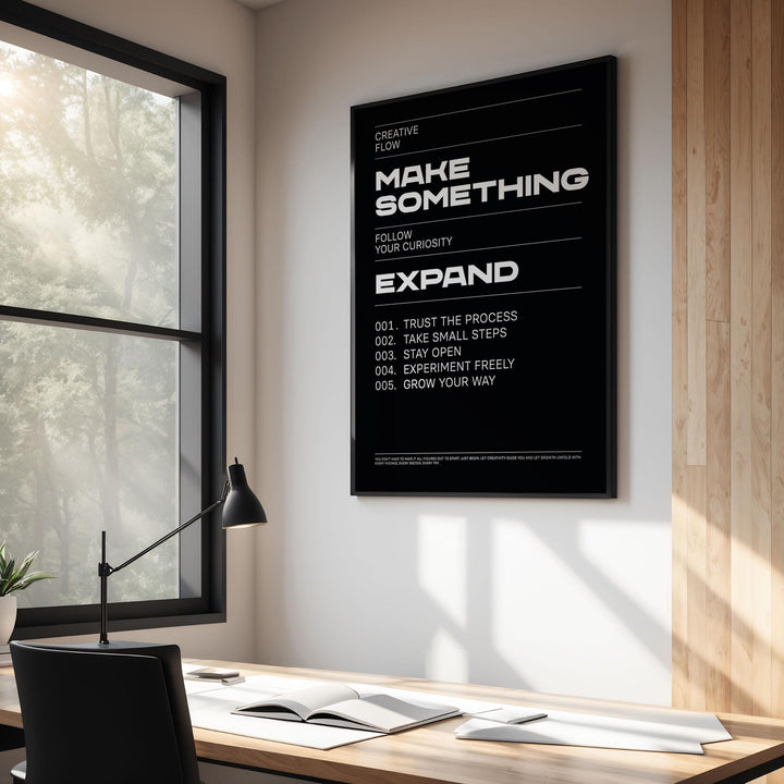 Wall Art Phrases print with white text on black in a frame on a white wall with a desk lamp nearby