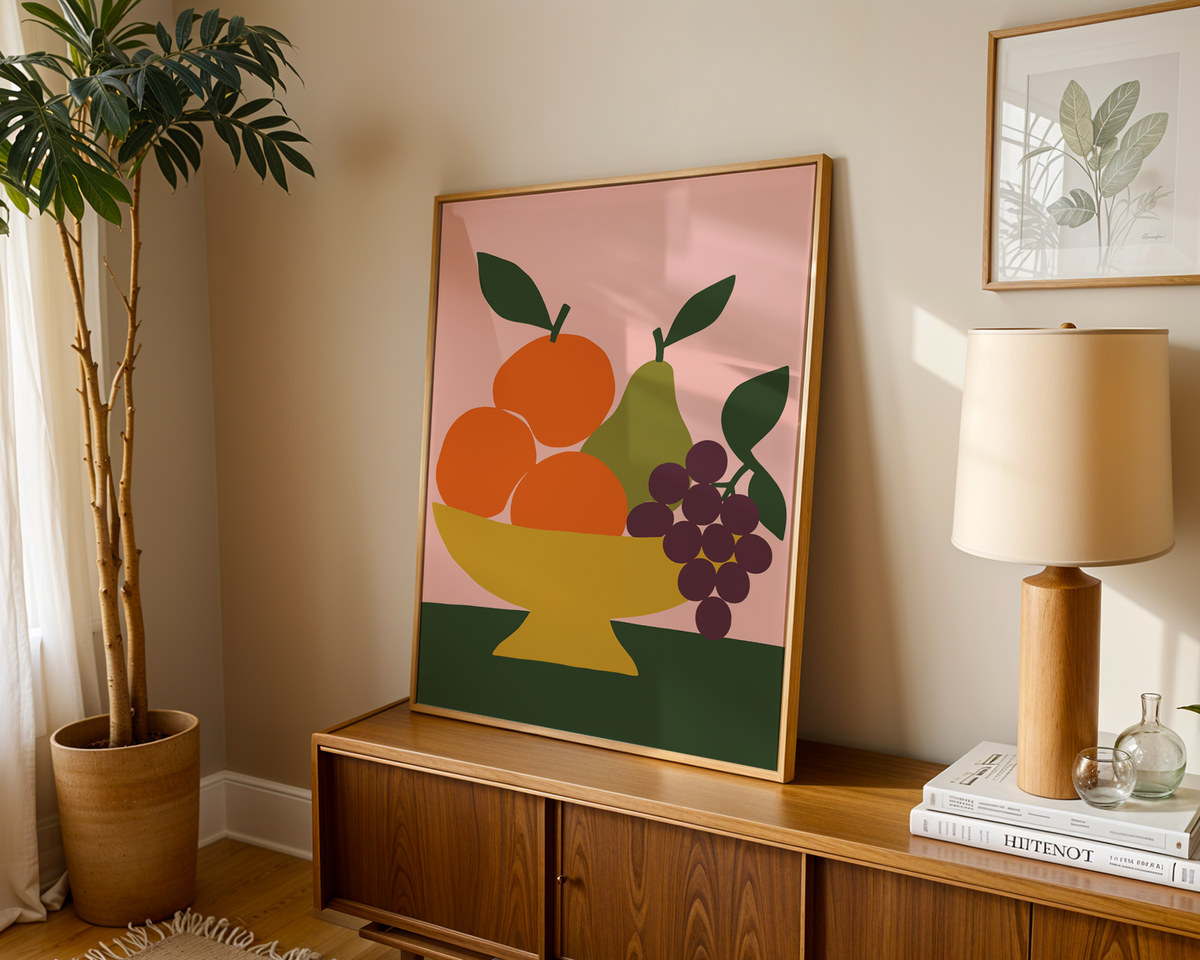 Fruit bowl print with oranges and grapes leaning on a wooden sideboard in a warm living room