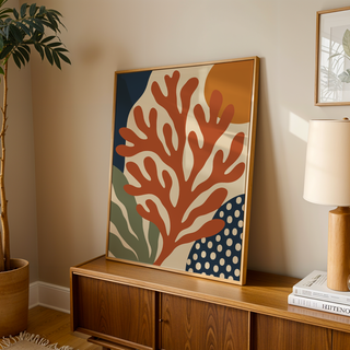 Coral wall art with an orange sun leaning on a wooden sideboard in a warm living room