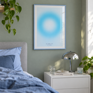 Pale cyan aura print in a bedroom against a stone green wall