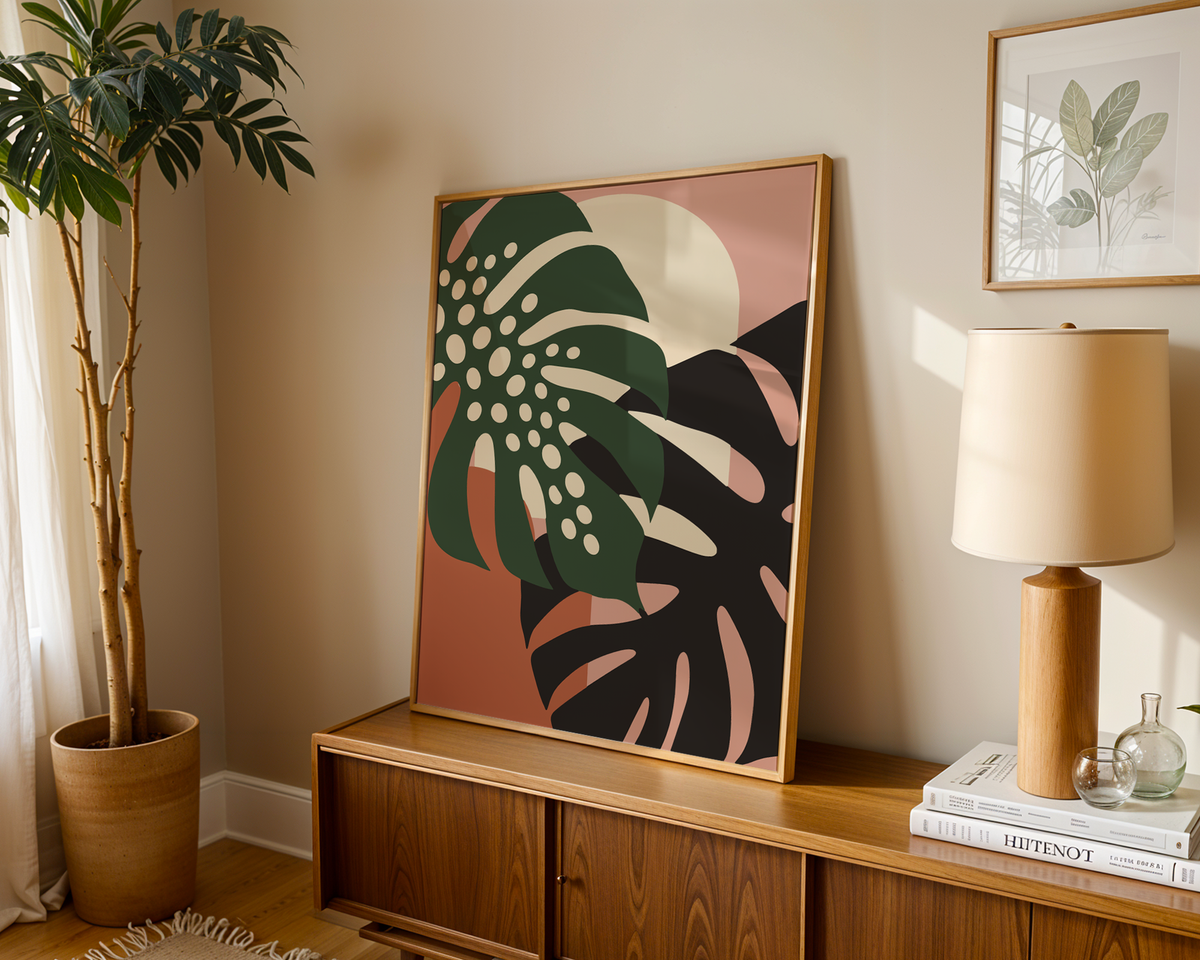 Tropical leaf print of two monstera leaves leaning on a wooden sideboard in a warm living room