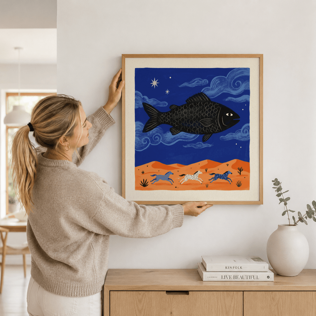 Illustrated poster print of a large fish over desert hills with three horses