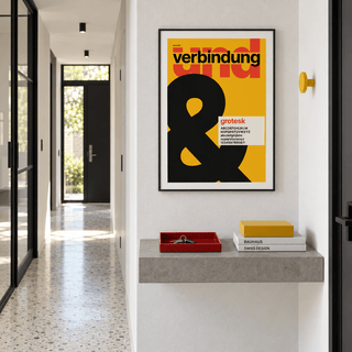 Ampersand on mustard yellow print above a console table in a hallway