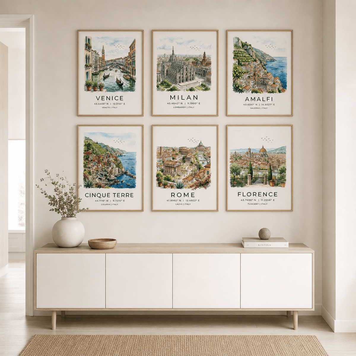 Framed artworks of famous cities on a wall above a white console table.