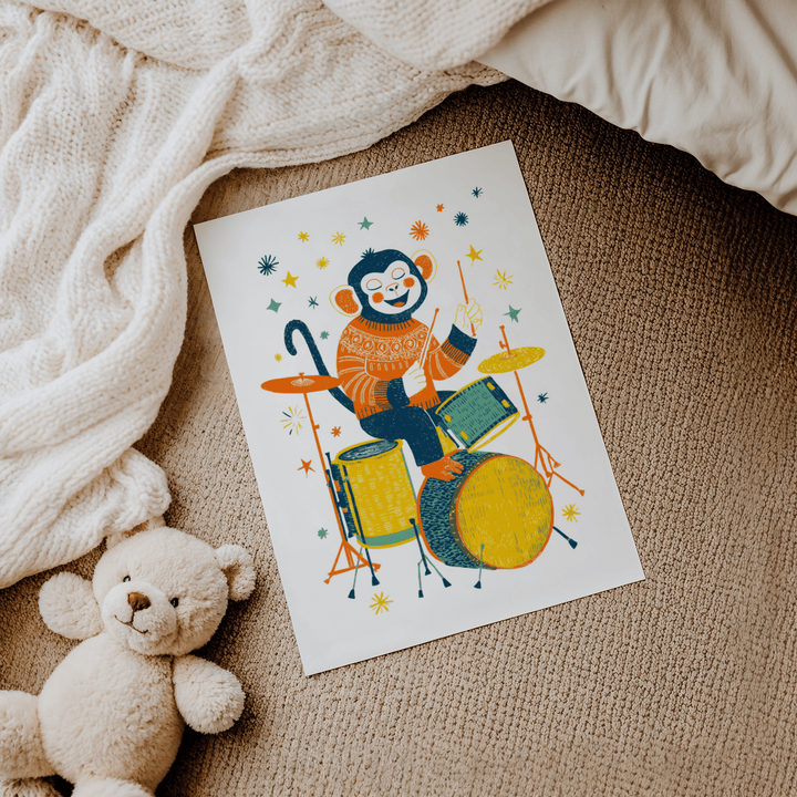 Monkey Drummer art print of a monkey playing drums with yellow and orange details on carpet next to teddy bear