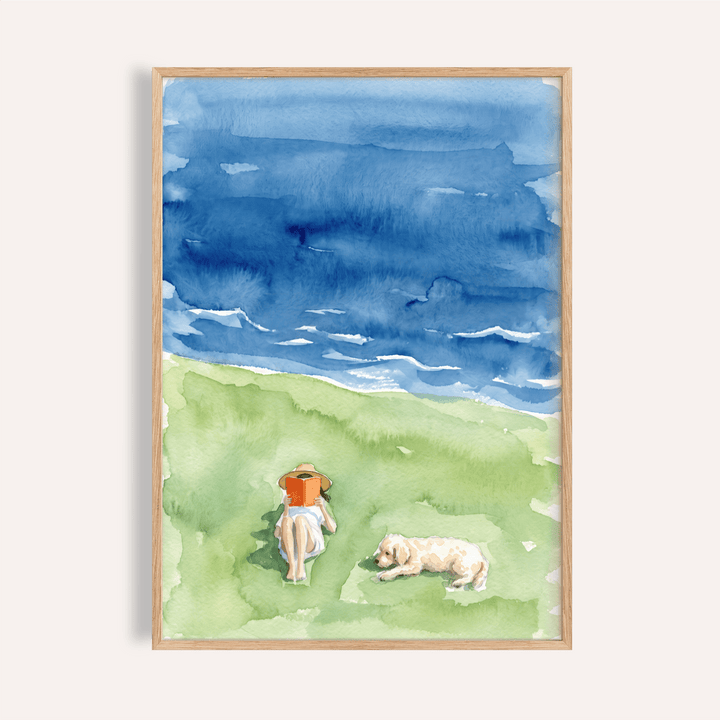 Above view watercolor wall art poster of a reader on grass by the sea with waves and a resting dog