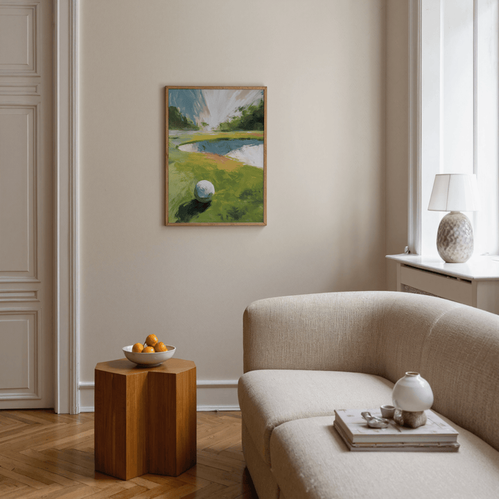 Golf Landscape wall art of a golf ball on a green fairway in a beige sitting room with a wooden side table