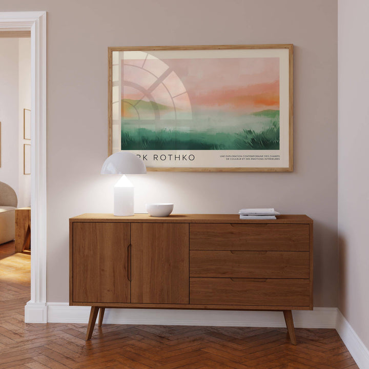 Framed pastel colored wall art above a mid-century wooden sideboard with a lamp and bowl