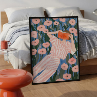 Illustrated figure wall art of a woman holding a book over her face in a floral field