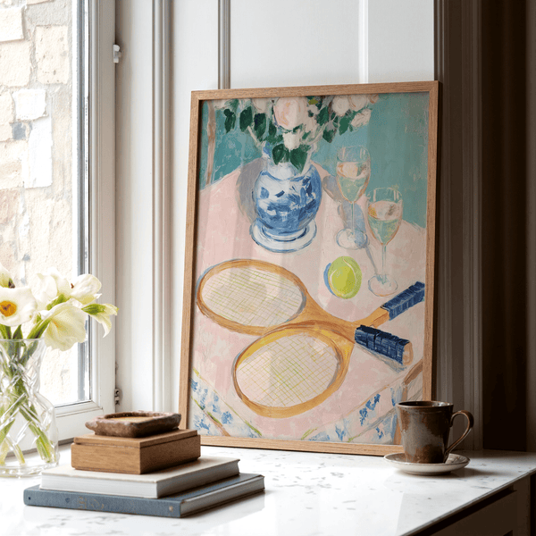Detailed wall art print of tennis ball beside two wine glasses in a still life scene