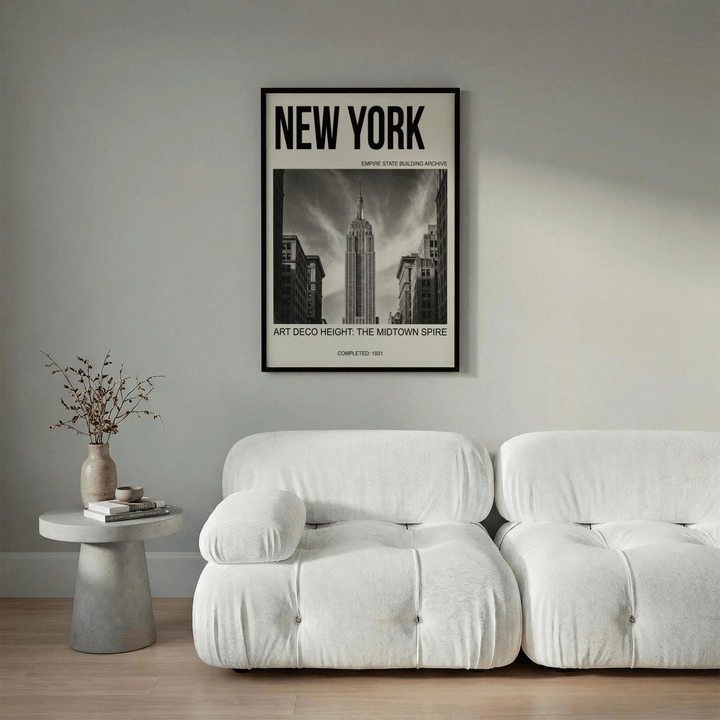 Empire State Building wall art in black and white above a white sofa with a side table and vase