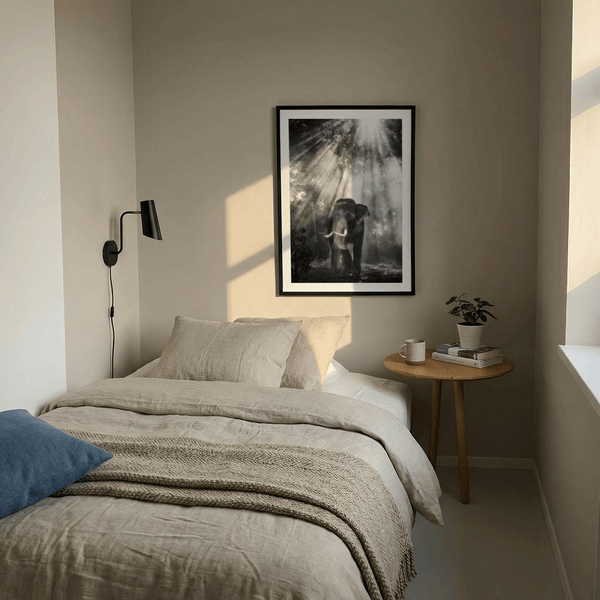 Elephant stands under towering trees with soft haze and light shafts