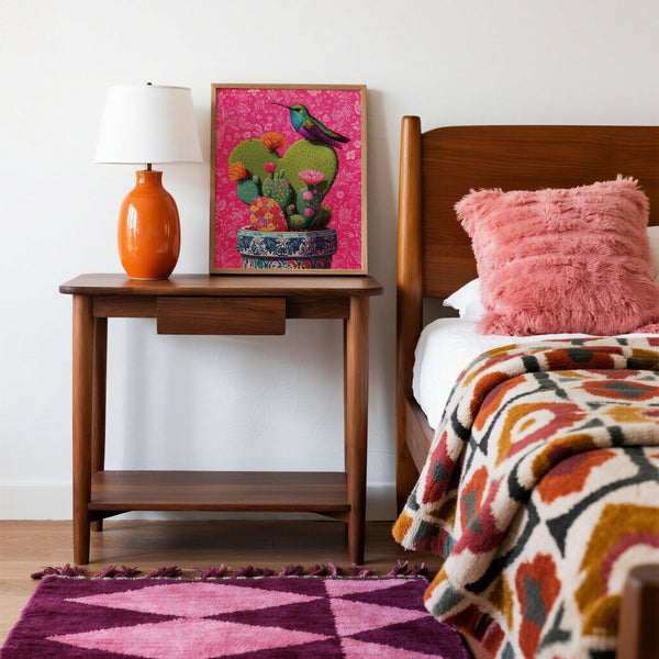 Pink floral background highlighting a corazon de nopal art print in a painted pot.