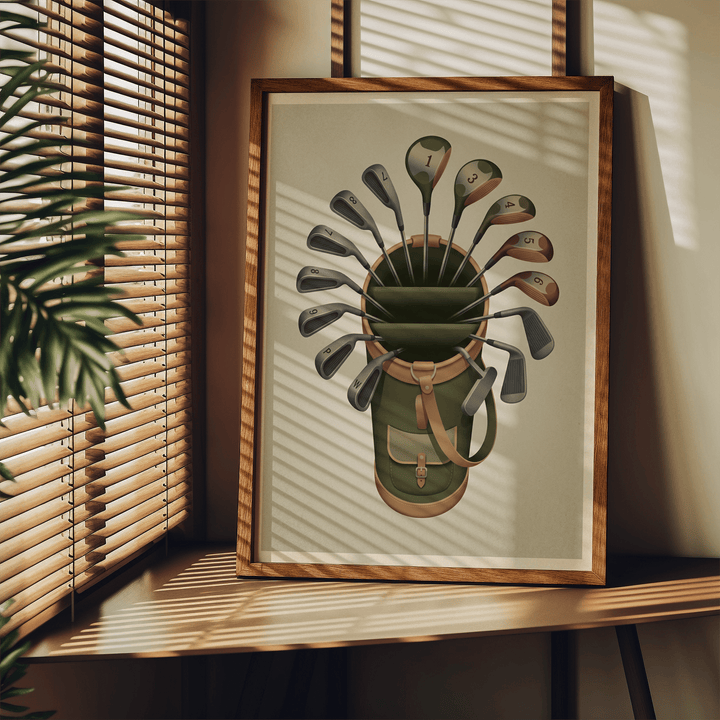 Framed golf clubs wall art leaning on a wooden table with shadows from blinds and a green plant nearby