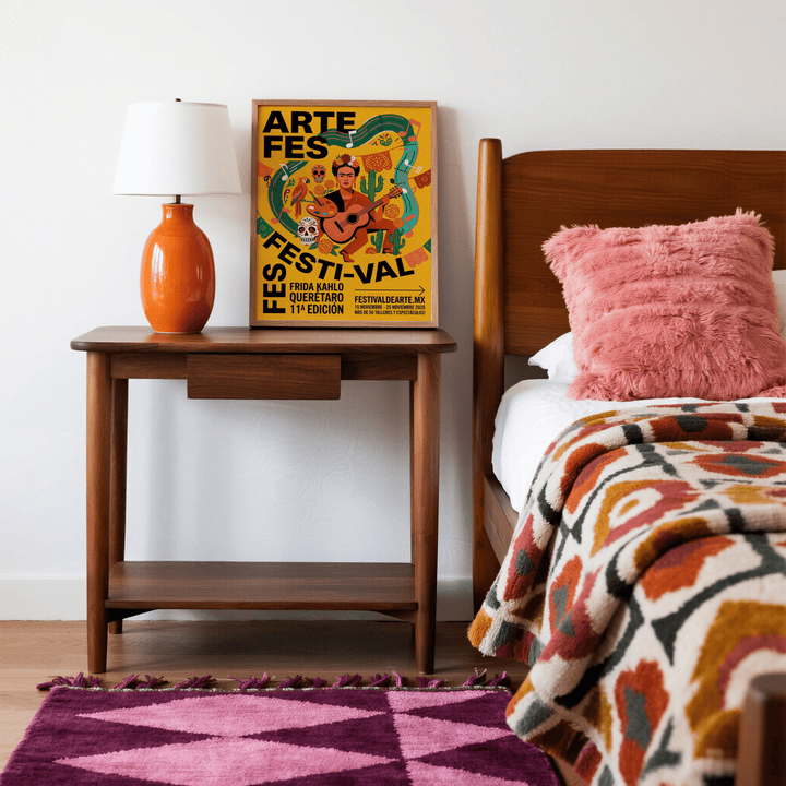 Frida Kahlo art print leaning on a wooden bedside table next to an orange lamp in a bedroom