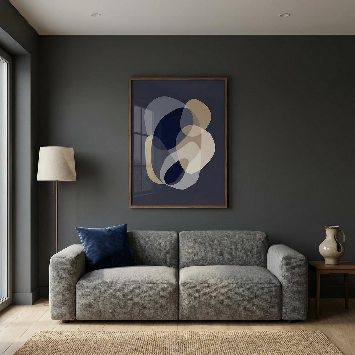 Modern living room with a gray sofa, abstract art on the wall, and a lamp.