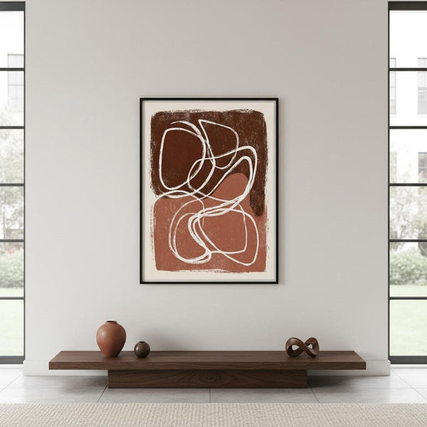 Abstract art piece on a wall with a wooden shelf below in a room with large windows.