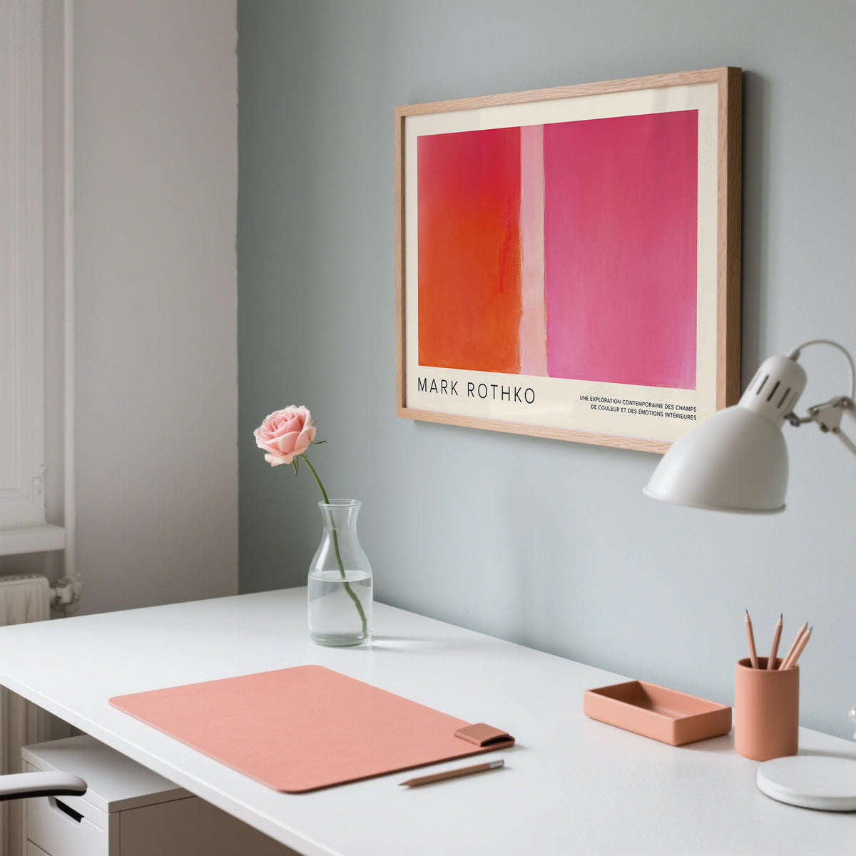 Modern office desk with a Mark Rothko print, pink mouse pad, and lamp.