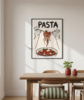 Framed artwork of hands holding pasta with a bowl of pasta below, on a wall above a dining table.