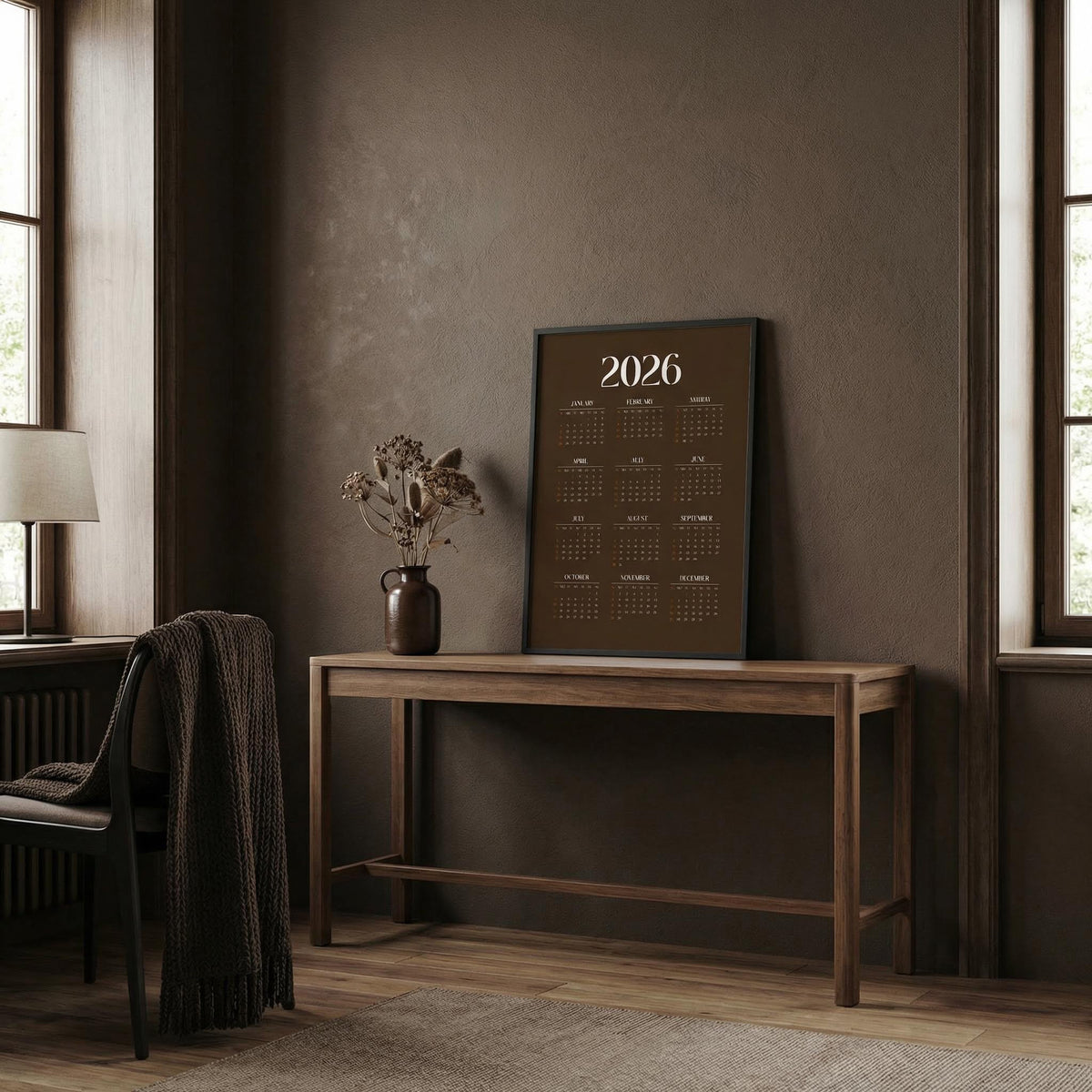 Calendar for 2026 on a wooden table in a room with a lamp and vase.