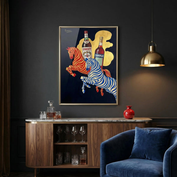 Framed artwork of two leaping zebras with Campari bottles on a dark wall above a wooden cabinet.