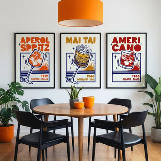 Dining room with a round table and black chairs, featuring three framed cocktail posters on the wall.