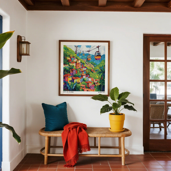 Colorful painting of a village scene above a bench with a blue pillow and red blanket, in a room with a plant and open door.