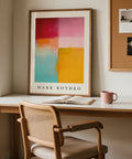 Abstract color block art print by Mark Rothko on a wall above a desk with a chair.
