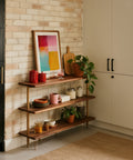 Wooden shelf with decorative items against a brick wall in a kitchen.