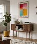 Modern living room with wooden console table, abstract color block art, and plant.