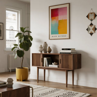 Modern living room with wooden console table, abstract color block art, and plant.