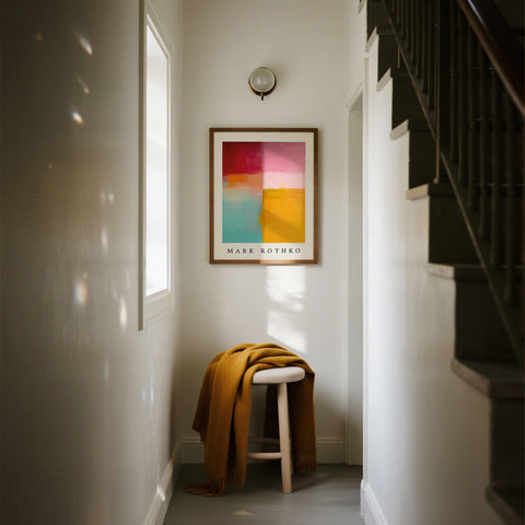 Abstract color block art painting on a wall above a stool with a yellow blanket in a room.