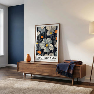 Floral artwork by Yayoi Kusama on a wooden console table in a room with a blue accent wall.