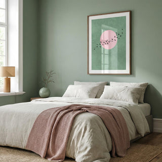 Bedroom with a bed, pink blanket, and framed artwork on a green wall.