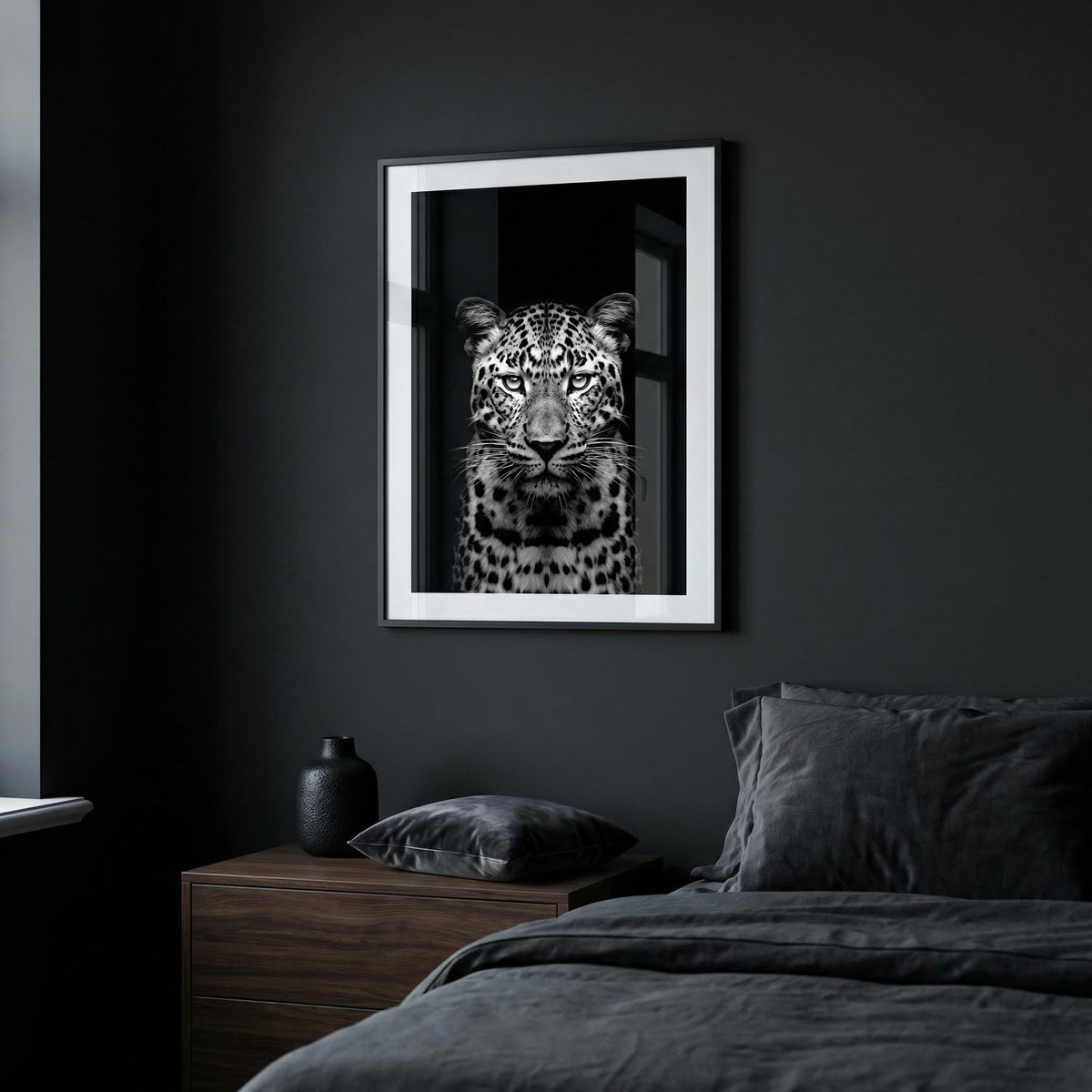 Framed artwork of a leopard on a dark wall above a bed.