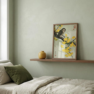 Framed artwork of a bird and flowers on a wall above a bed with pillows.