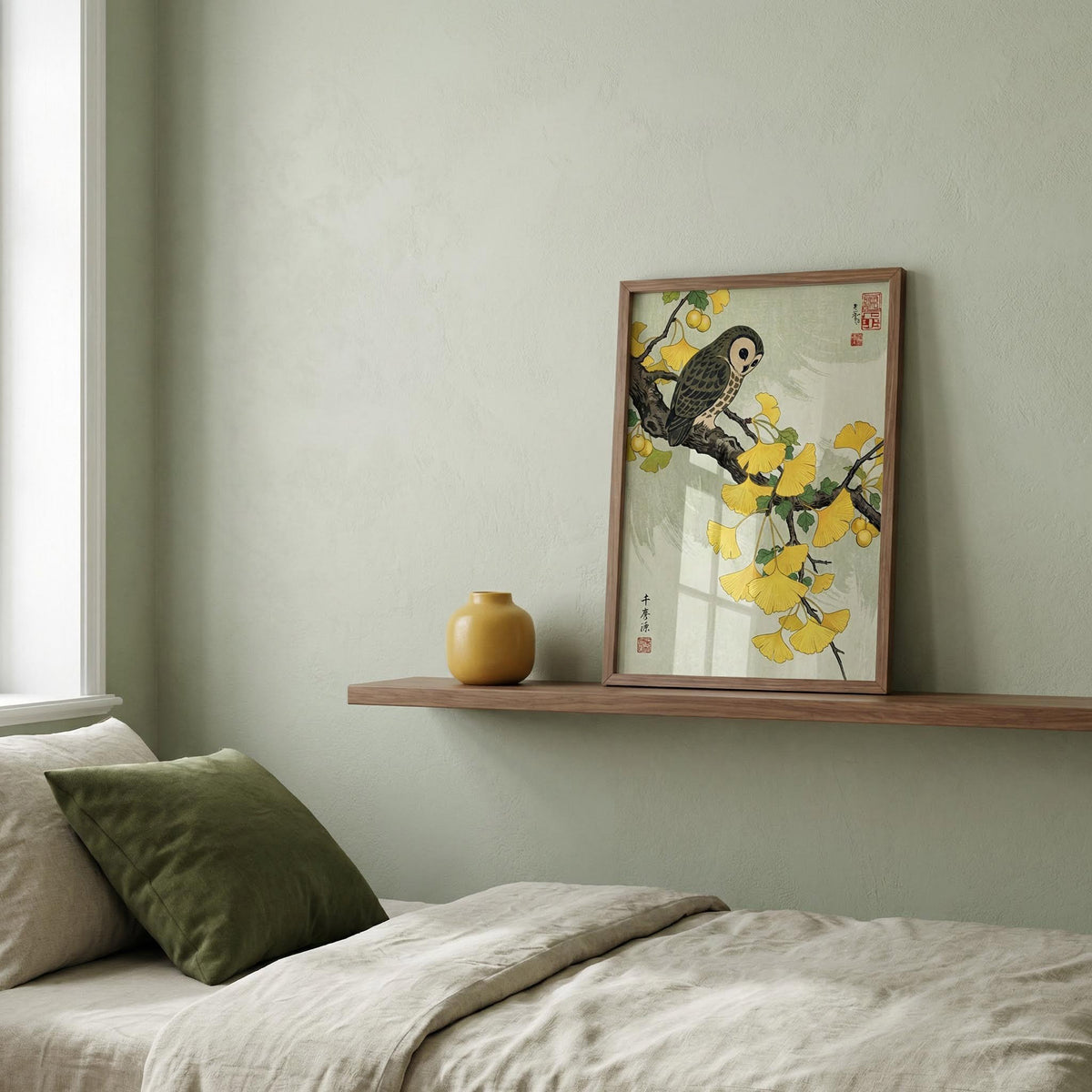 Framed artwork of a bird and flowers on a wall above a bed with pillows.