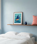 Framed artwork of a sailboat on a shelf above a bed with a pink pillow.