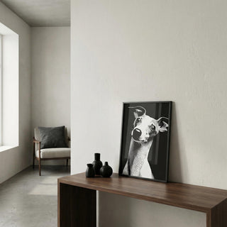 Framed black and white artwork of a dog on a wooden console table in a minimalistic room.